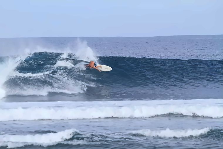 Deano carving back toward the pocket on a clean left at Ujung Bocur, the empty lineup stretching behind him