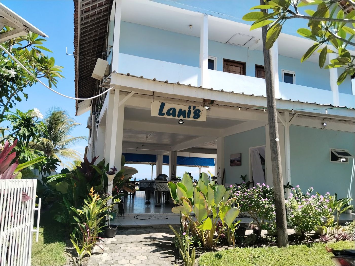 The white two-storey Lani's Resto & Room building in Tanjung Setia — balcony rooms upstairs, open-air restaurant below