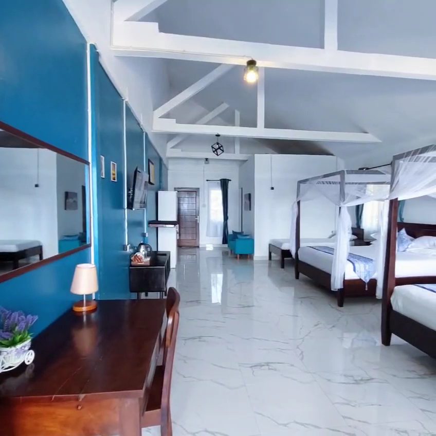 Bright guest room at Lani's Resto & Room, Tanjung Setia — four-poster beds, marble floor, ocean through the window